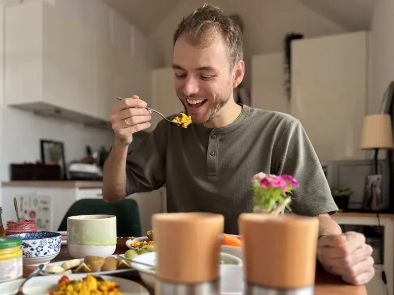 Marvin, der lachend einen Bissen Scrambled Tofu isst