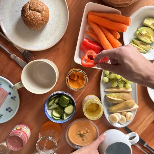 Zwei Hände greifen nach Essen, das auf dem Tisch steht