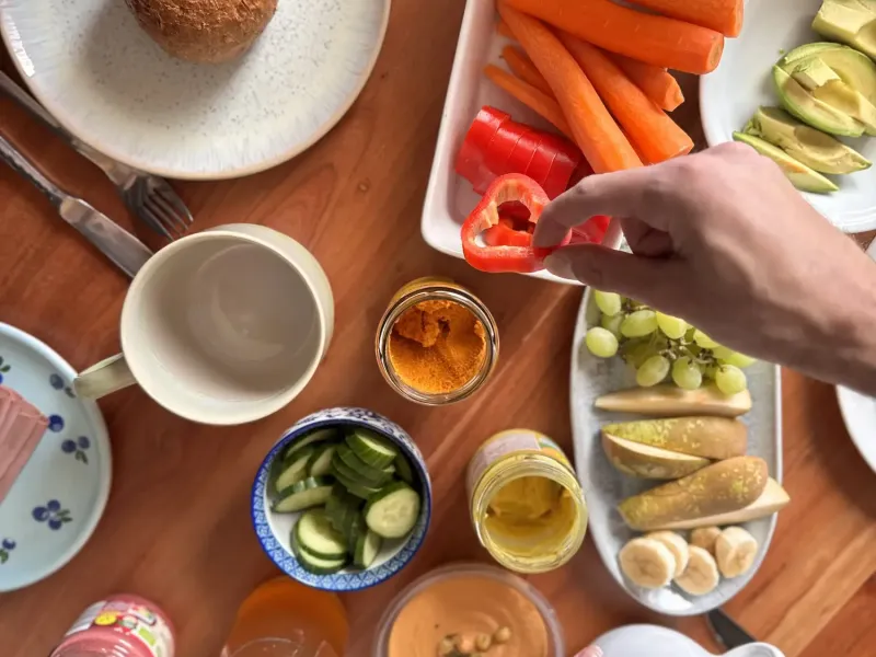 Zwei Hände greifen nach Essen, das auf dem Tisch steht