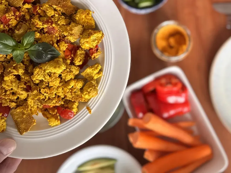 Teller Scrambled Tofu, der über den Tisch gehalten wird
