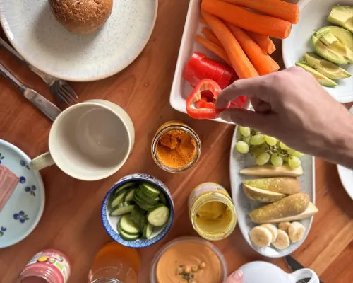 Zwei Hände greifen nach Essen, das auf dem Tisch steht